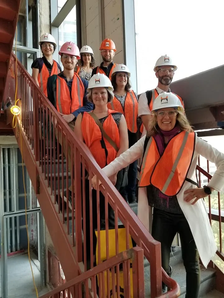 Project team in hard hats and safety vests on a courthouse stair during construction