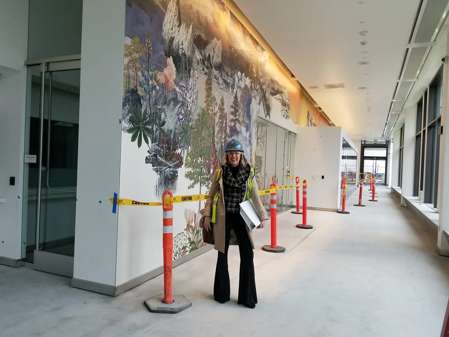 Summer Fowler in a hard hat on a construction walk past an interior mural
